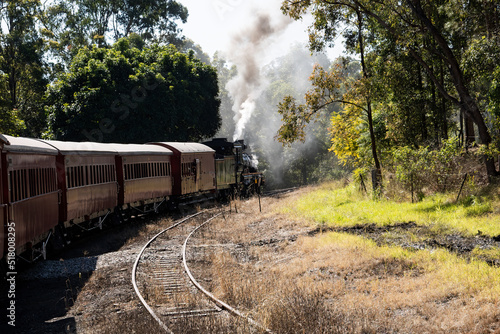 Historic Mary Valley Rattler steam engine with vintage carriages rounding a curve on the line at Gympie, Queensland. photo
