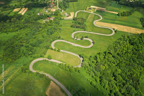 Aerial drone view of winding road between green forest