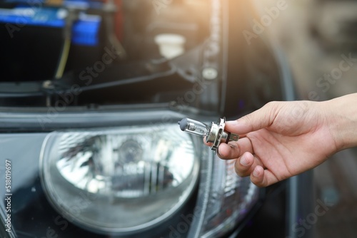 Man mechanic changing car headlight bulb in hand on car headlight background . Repairing car.