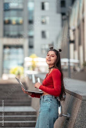 Beautiful young woman on the street using laptop