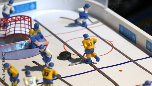 Miniature figure of hockey player turns near small puck on field of table top game closeup. Sportive table game photo