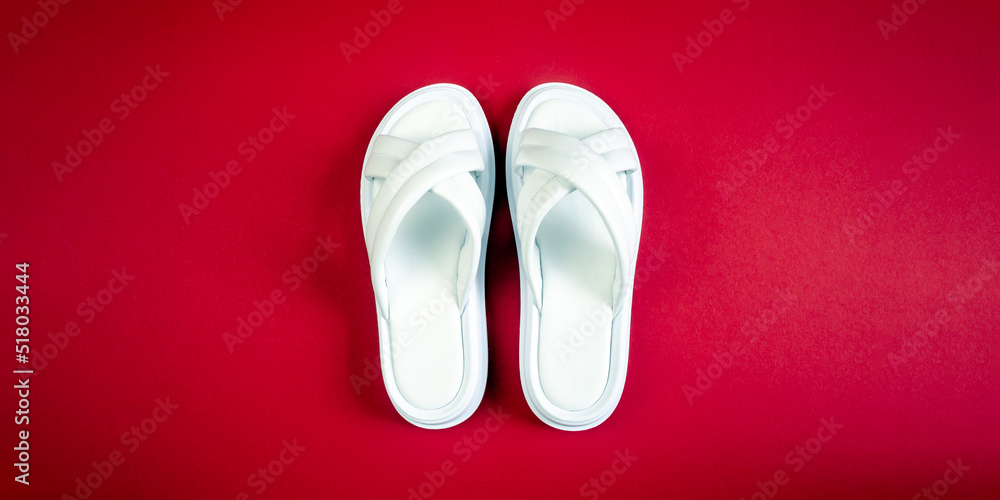 Women's summer white slippers on a red background. Slippers. Horizontal image Women's summer white slippers on a red background. Slippers. Horizontal image