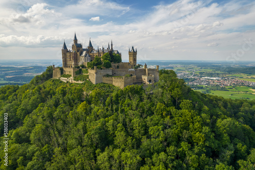 Drone shot of Hohenzollern Castle on forested mountain top in the Swabian Alps in summer. Scenic aerial view of old German Burg. Famous fairytale Gothic landmark in Stuttgart vicinity