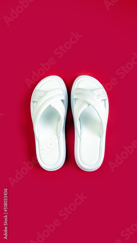 Women's summer white slippers on a red background. Slippers. Vertical image