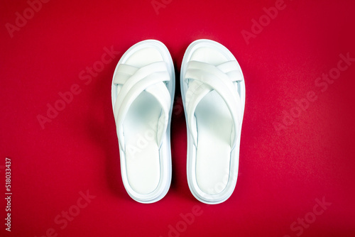 Women's summer white slippers on a red background. Slippers. Horizontal image
