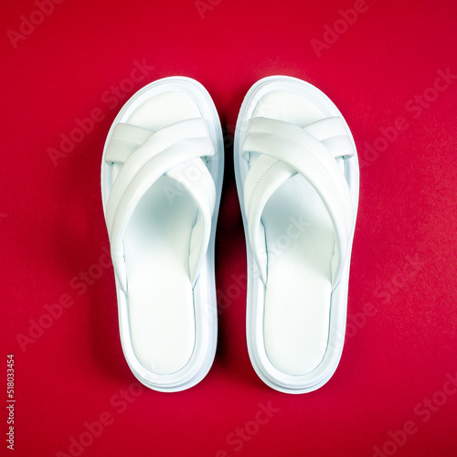 Women's summer white slippers on a red background. Slippers. Square image