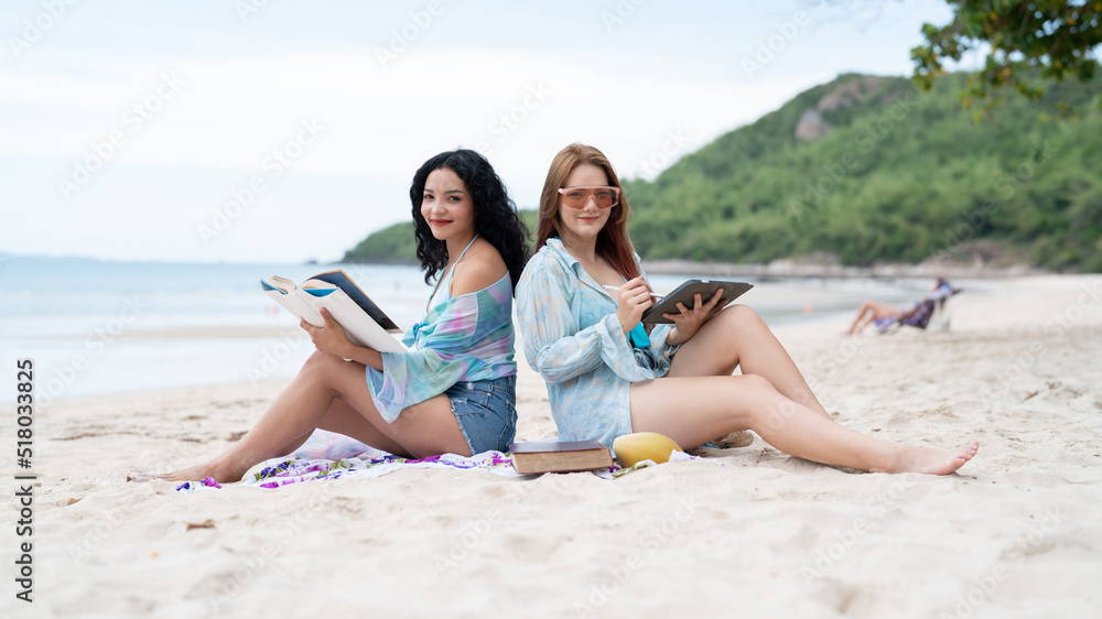 two girls sitting on a laptop and read books on vacation holiday concept travel lgbtq two girls sitting on a laptop and read books on vacation holiday concept travel lgbtq