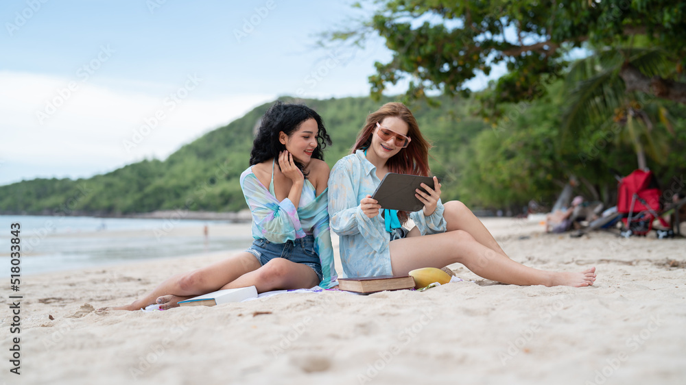 two girls sitting on a laptop and read books on vacation holiday concept travel lgbtq
