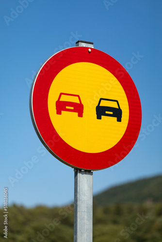 Señal vertical, de tráfico adelantamiento prohibido por obras sobre un cielo azúl (amarillo, rojo, azul, negro)