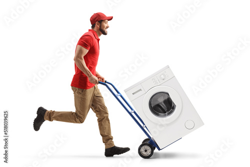 Full length profile shot of a male worker running and pushing a hand-truck with a washing machine photo