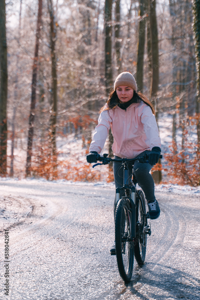 A woman rides a bike in winter. Concept of cycling during snowy weather. Snow and sun weather in the park A woman rides a bike in winter. Concept of cycling during snowy weather. Snow and sun weather in the park