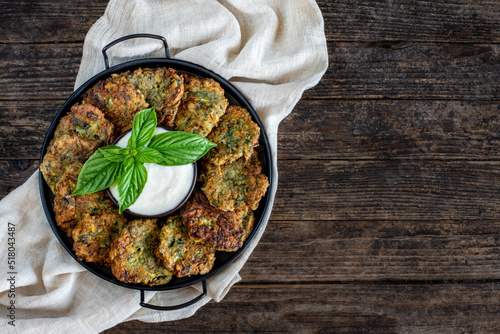 Many vegetable flitters in the plate with white sauce.