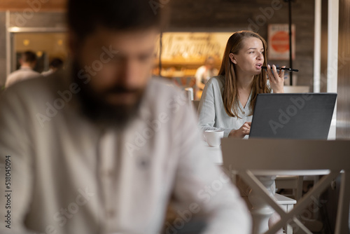 businesswoman working in cafe using laptop, freelancer work in coffee shop, man in foreground