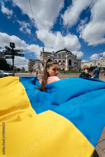 Young woman carries the flag of Ukraine fluttering behind her © teksomolika
