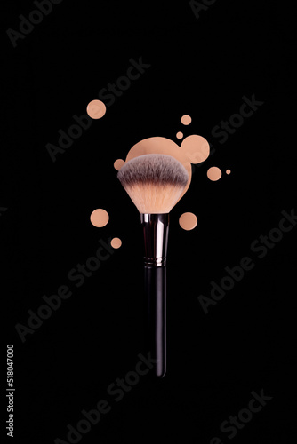 Professional brush with black handle for make up with drops of beige foundation, bb cream isolated on black
