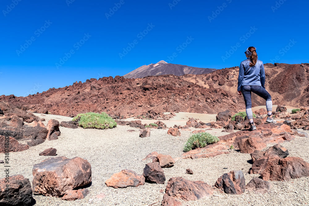Rear view of hiking woman with scenic view on moon landscape of Minas de San Jose Sur near volcano Pico del Teide, Mount El Teide National Park, Tenerife, Canary Islands, Spain, Europe. Lava rocks