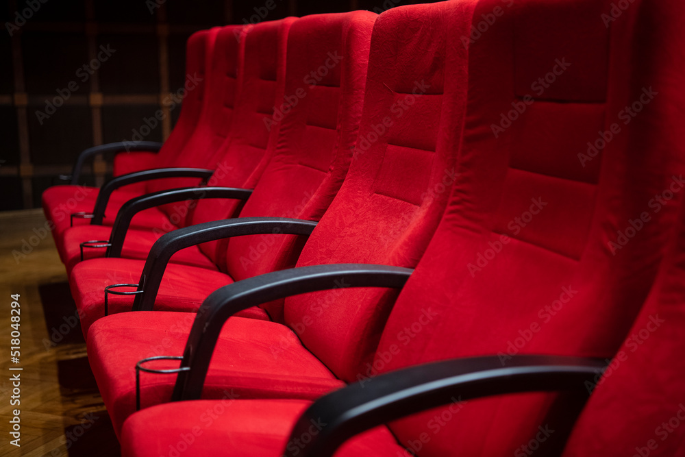 Obraz premium Cinema movie theater background. Red cozy cinema seats in empty theater. Armchairs with comfortable elbows.