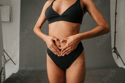 African American female making a heart shape with her hands on her well toned abdomen
