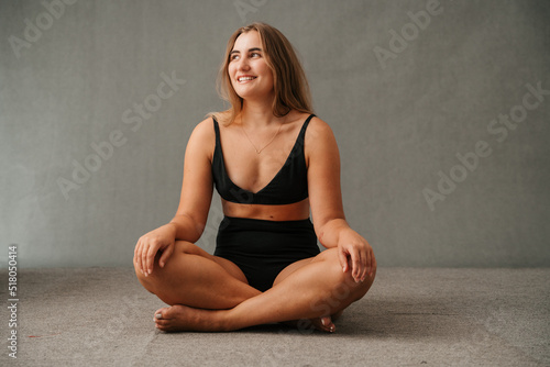 Attractive female sitting cross legged bare foot in the studio on the floor