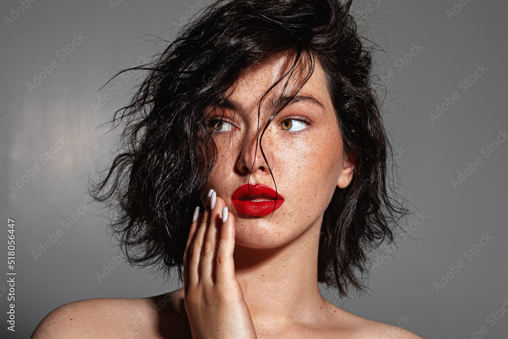 Φωτογραφία beauty young woman face with a lot of freckles and red lips, hand near face, clo
