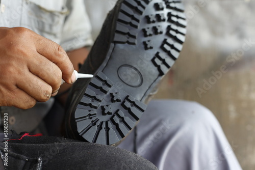 Loose leather shoe soles are being reattached with strong glue. Isolated on a shoe repairman manually. Isolated on Repairing broken shoes by a shoe repairman.