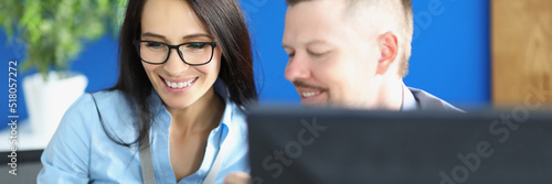 Woman and man workers in office discuss something and laugh