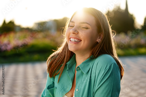 Portrait of young woman in green shirt smiling in a park photo