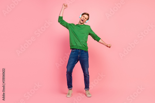 Young man listening music wireless headphones dance active enjoying favorite tracks isolated pastel background