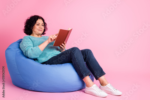 Full length body size photo of woman sitting in chair reading book happy isolated on pastel pink color background