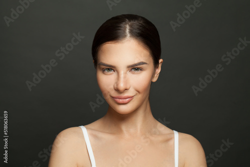 Gorgeous brunette woman with clean healthy skin smiling on black background