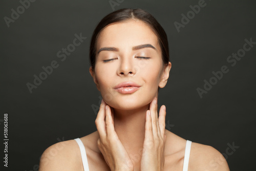 Cute woman with smooth healthy clean skin posing on black background. Skincare and facial treatment concept