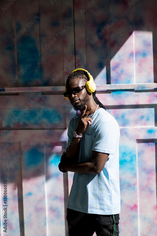 Fototapeta premium black guy with headphones with multicolored wall in the back