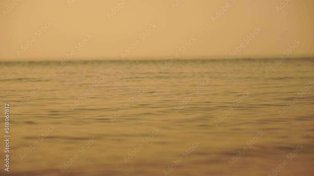 Abstract calm sea summer ocean sunset nature background. Small waves on water surface in motion blur with golden bokeh lights from sun. Holiday, vacation and recreational concept. Slow motion Abstract calm sea summer ocean sunset nature background. Small waves on water surface in motion blur with golden bokeh lights from sun. Holiday, vacation and recreational concept. Slow motion