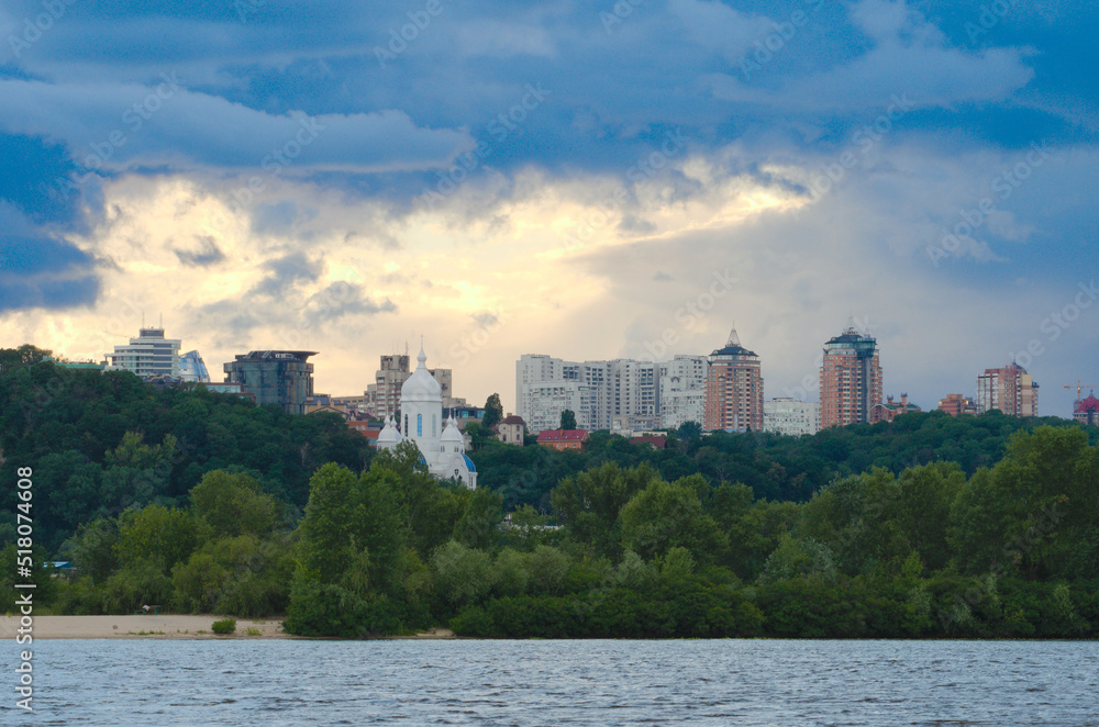 Panoramic landscape cityscape of Kyiv. Modern multi-story apartment buildings on horizon. Stormy sky and gloomy clouds. River Dnipro on foreground. Travel and tourism concept