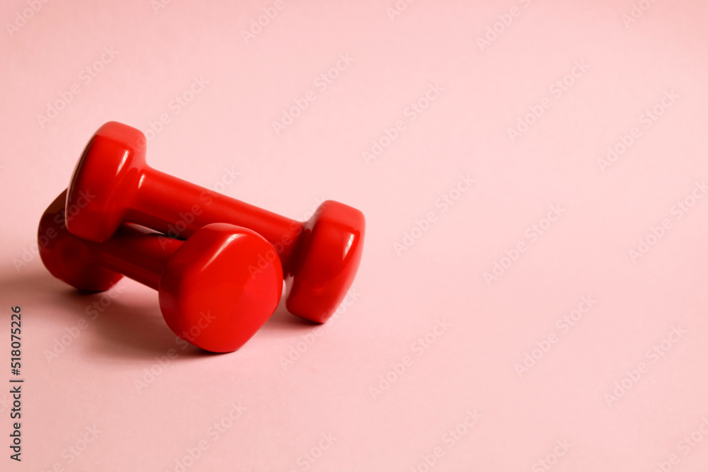 Two red dumbbells on a pink background. Sports equipment flat lay background Two red dumbbells on a pink background. Sports equipment flat lay background