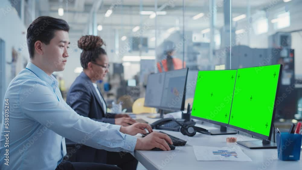Factory Office Room: Industrial Engineers Developing Models of a Heavy Industry Machine Parts on a Computer 3D Software. Two Computer Monitor Displays are a Green Screen Mock Up Template. Factory Office Room: Industrial Engineers Developing Models of a Heavy Industry Machine Parts on a Computer 3D Software. Two Computer Monitor Displays are a Green Screen Mock Up Template.
