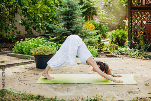 Young woman practices yoga in the garden - Parvatasana, Mountain Pose photo