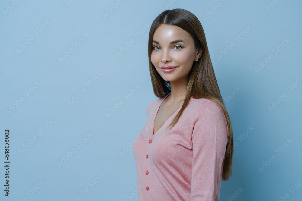 Profile shot of beautiful charming brunette woman has long straight hair, wears casual pink jumper, thinks and makes up plan, isolated over blue background, blank space for your promotion or text Profile shot of beautiful charming brunette woman has long straight hair, wears casual pink jumper, thinks and makes up plan, isolated over blue background, blank space for your promotion or text