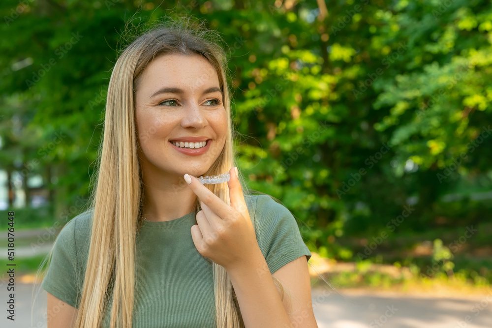 Young beautiful woman wearing green t shirt over holding an invisible aligner. Dental healthcare and confidence concept. Places for text Young beautiful woman wearing green t shirt over holding an invisible aligner. Dental healthcare and confidence concept. Places for text