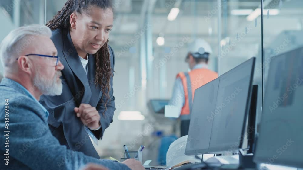 Factory Office Facility: Industrial Engineers Drafting Blueprints of a Heavy Industry Machine Parts on a Computer CAD Software. African American Technician Discusses Work with Middle Aged Designer. Factory Office Facility: Industrial Engineers Drafting Blueprints of a Heavy Industry Machine Parts on a Computer CAD Software. African American Technician Discusses Work with Middle Aged Designer.