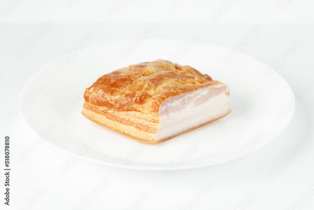 Smoked bacon, pork belly on a white plate, close-up. Smoked bacon, pork belly on a white plate, close-up.