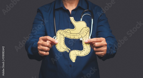 Fotografie Hand of the doctor holding a colon symbol while standing on a gray background