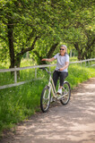A mid aged woman riding a bike in a park