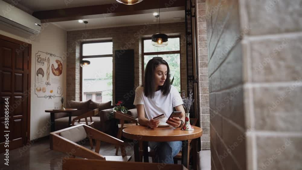 A young woman makes purchases through a smartphone with a bank credit card A young woman makes purchases through a smartphone with a bank credit card