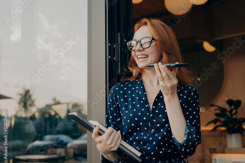 Foto Woman with red hair holds phone talks on speakerphone with friend makes voice re