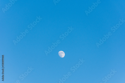 Moon against blue sky in the countryside.