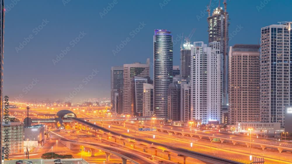 Dubai Marina skyscrapers and Sheikh Zayed road with metro railway aerial night to day transition timelapse. Traffic on a highway near modern towers before sunrise, United Arab Emirates Dubai Marina skyscrapers and Sheikh Zayed road with metro railway aerial night to day transition timelapse. Traffic on a highway near modern towers before sunrise, United Arab Emirates