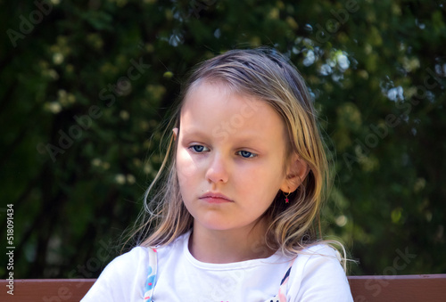 portrait of a sad pensive little girl 7 years old with long blond hair