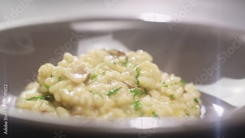 Serving of risotto with mushroom in a plate, slow motion. photo