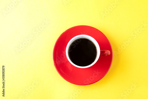 黄色の紙の上の赤いコーヒーカップのコーヒー